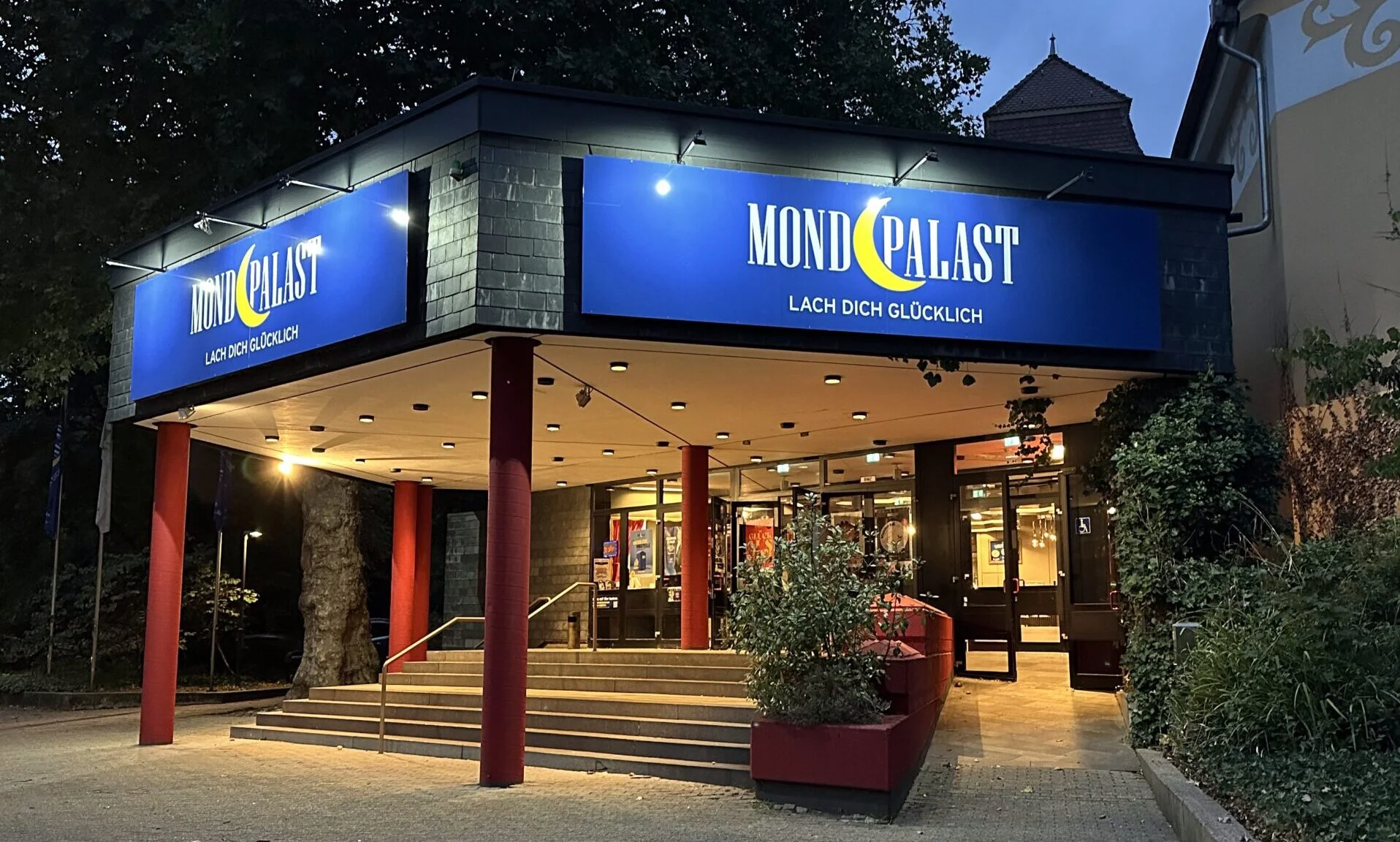 Der beleuchtete Eingang des Mondpalasts mit Treppe und seitlicher Rampe